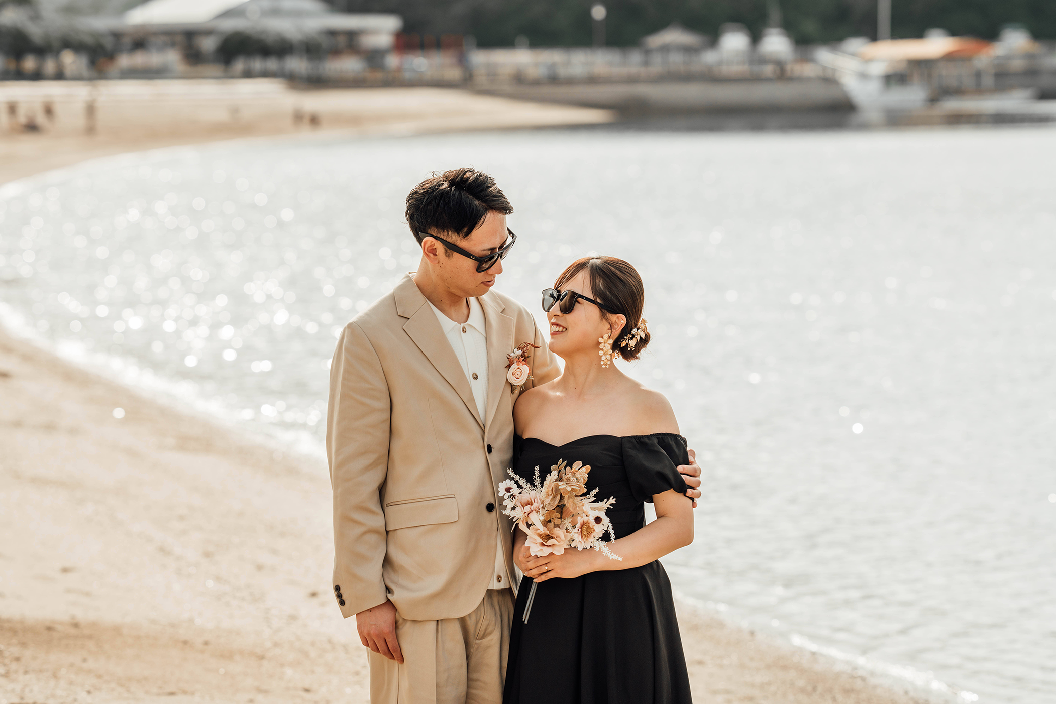 海岸でサングラスをかけて見つめ合うカップル